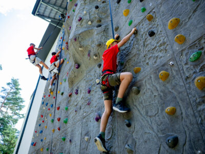 Dzieci wspinają się po ścianie wspinaczkowej. Aktywność, sport, zabawa.