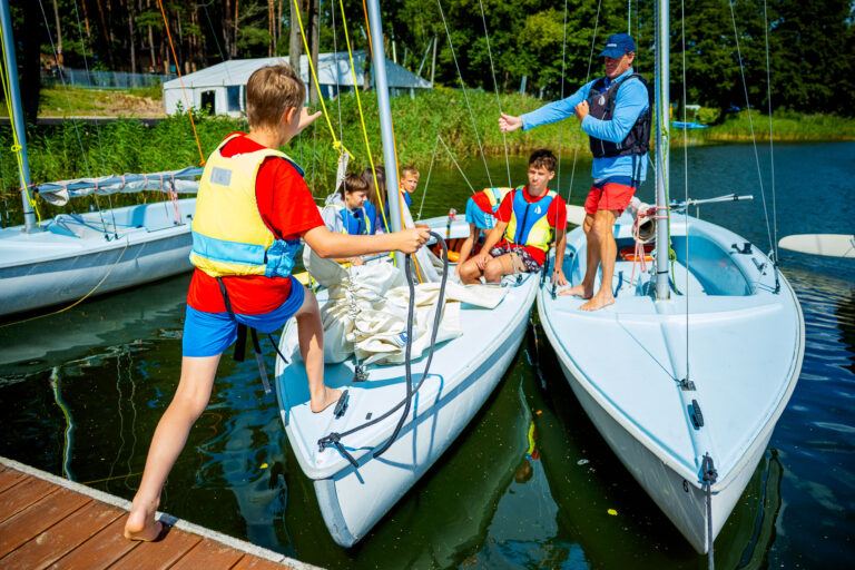 Dzieci uczą się żeglarstwa na jeziorze. Szkolenie żeglarskie dla młodzieży.
