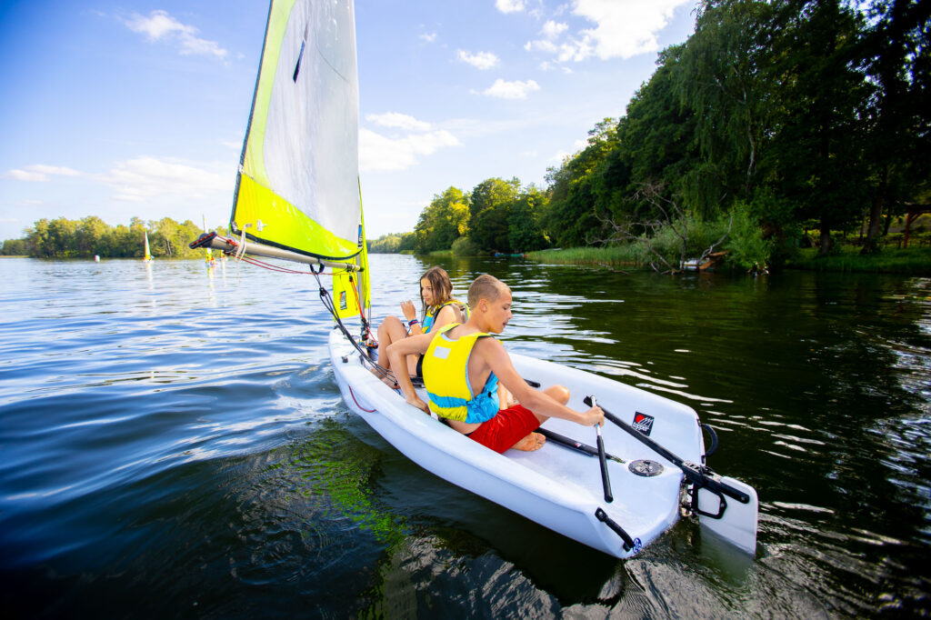 Dzieci żeglują na jeziorze w słoneczny dzień.
