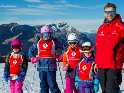 Grupa narciarzy w kaskach i goglach na tle gór.