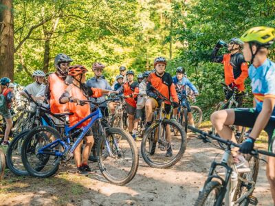 Grupa dzieci w kaskach na rowerach górskich w lesie. Przygoda i sport na świeżym powietrzu.
