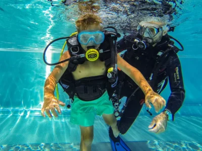 Dziecko nurkuje z instruktorem pod wodą. Nauka nurkowania dla dzieci.