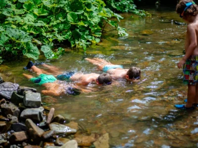 Dzieci nurkują i pływają w strumieniu. Letnia zabawa na łonie natury.
