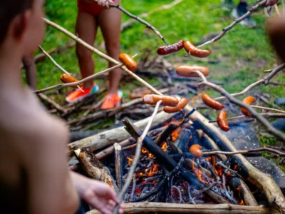 Kiełbaski pieczone nad ogniskiem. Letnie grillowanie, przyroda, dzieci.
