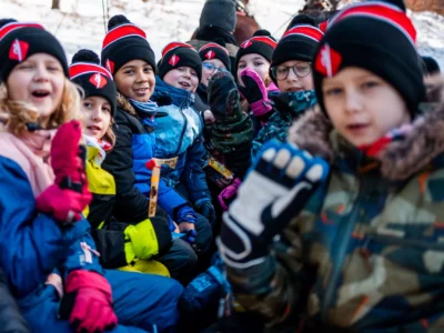 Dzieci w zimowych czapkach i rękawiczkach, gotowe na przygodę na śniegu.