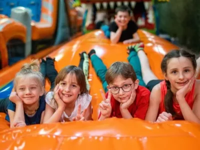 Dzieci bawią się na dmuchanej zjeżdżalni. Radość i zabawa na placu zabaw.