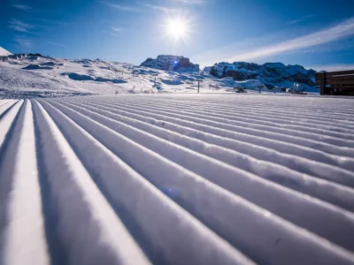 Przygotowany stok narciarski z idealnymi ratrakami. Słońce, góry i błękitne niebo.