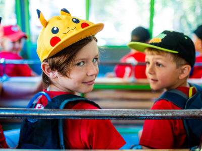 Dzieci w czapkach Pikachu i z plecakami. Radosne, letnie chwile.