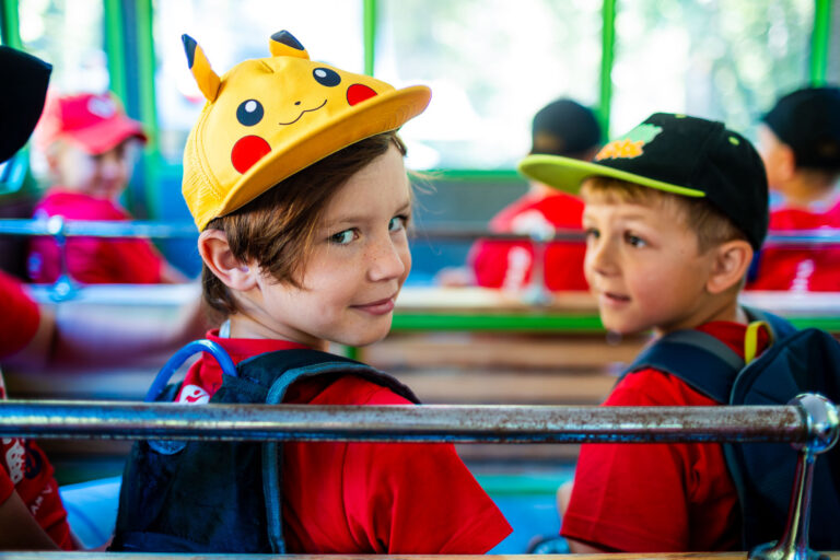 Dzieci w czapkach Pikachu i z plecakami. Radosne, letnie chwile.