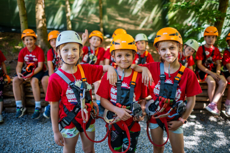 Dzieci w kaskach i sprzęcie wspinaczkowym gotowe na przygodę. Bezpieczeństwo i zabawa!