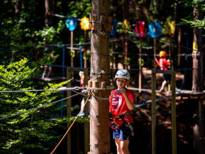 Dziecko w kasku na parku linowym, przygotowuje się do przejścia trasy. Bezpieczeństwo i zabawa na wysokości.