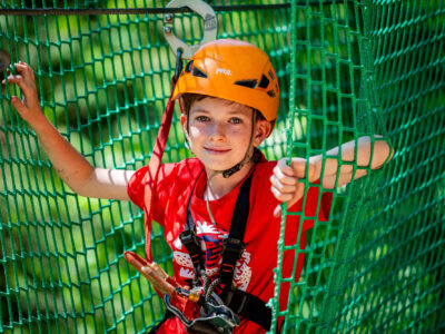 Chłopiec w kasku na parku linowym. Przygoda i zabawa na wysokości.