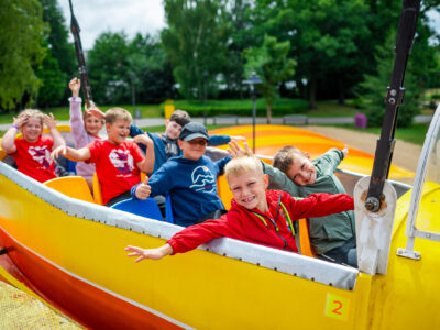 Radosne dzieci na żółtej kolejce górskiej w parku rozrywki. Zabawa i uśmiechy!
