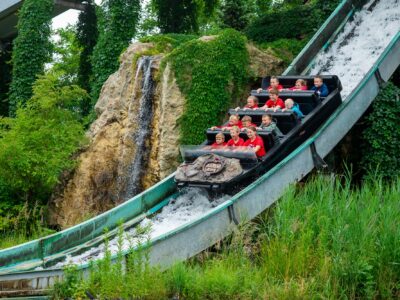 Dzieci z radością zjeżdżają łódką po wodnej zjeżdżalni. Park rozrywki, atrakcje wodne.