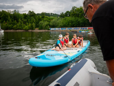 Dzieci na desce SUP na jeziorze. Aktywny wypoczynek na wodzie.