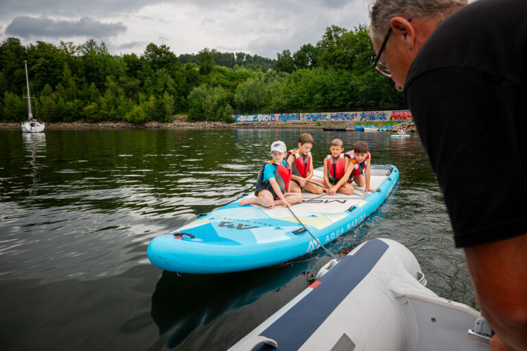 Dzieci na desce SUP na jeziorze. Aktywny wypoczynek na wodzie.