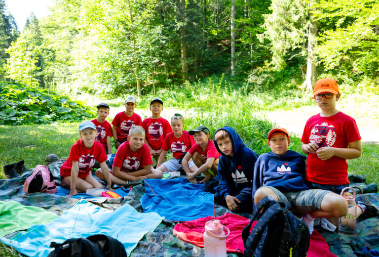 Dzieci w lesie na pikniku. Grupa młodych ludzi cieszy się przyrodą.