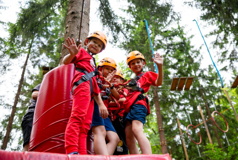 Dzieci w kaskach i szelkach na parku linowym. Radosna zabawa na wysokościach!