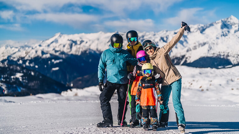 Rodzina na nartach w górach. Szczęśliwe dzieci i rodzice cieszący się zimową przygodą.