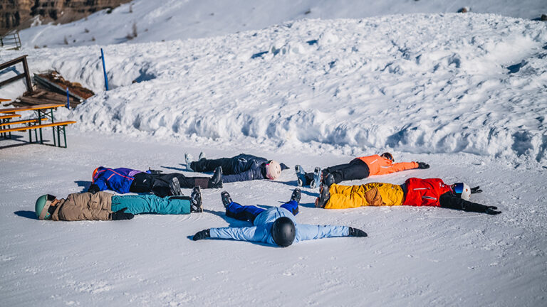 Grupa narciarzy leży na śniegu w kształcie gwiazdy.