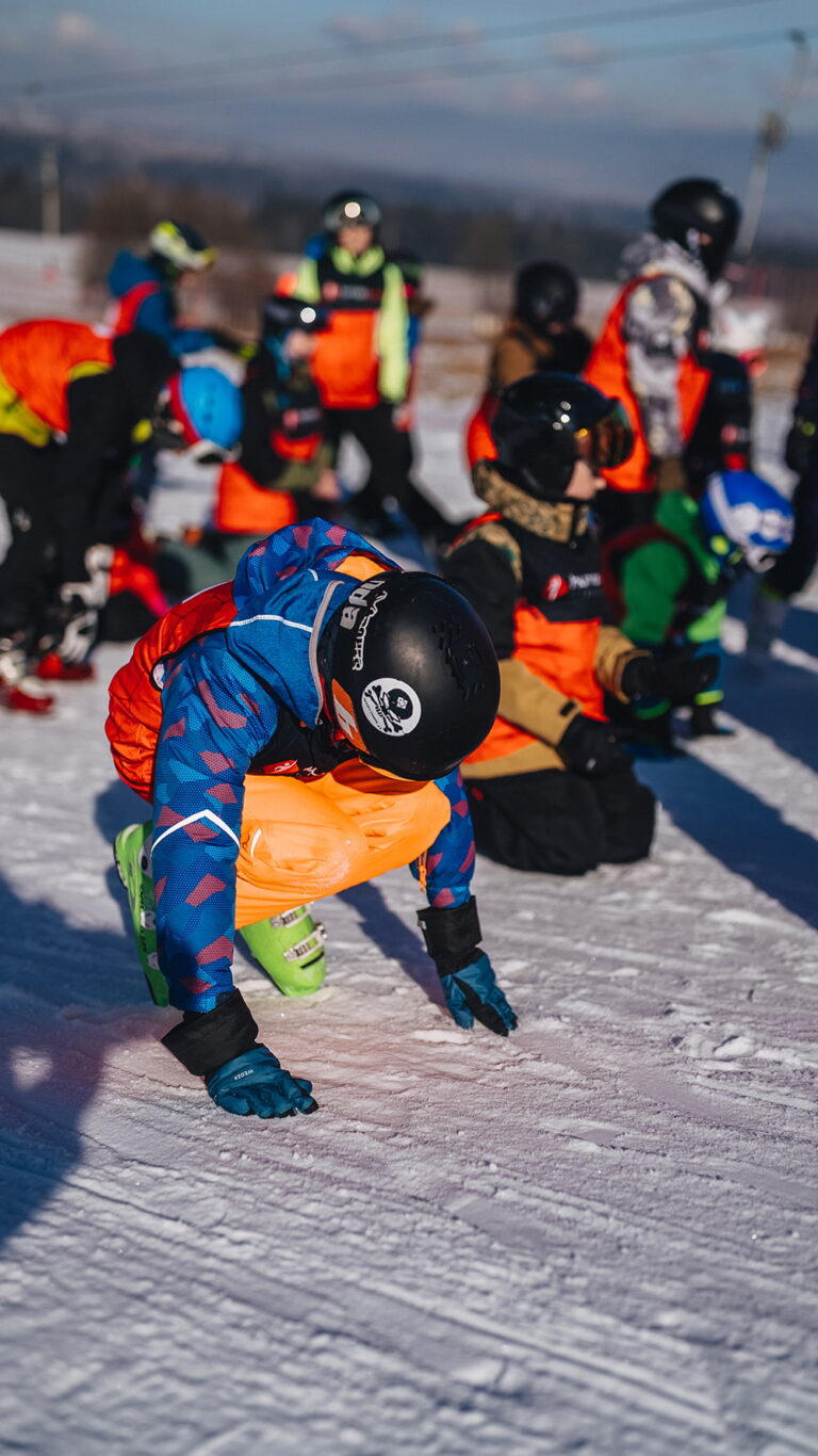 Dzieci w strojach narciarskich na stoku. Nauka jazdy na nartach dla najmłodszych.