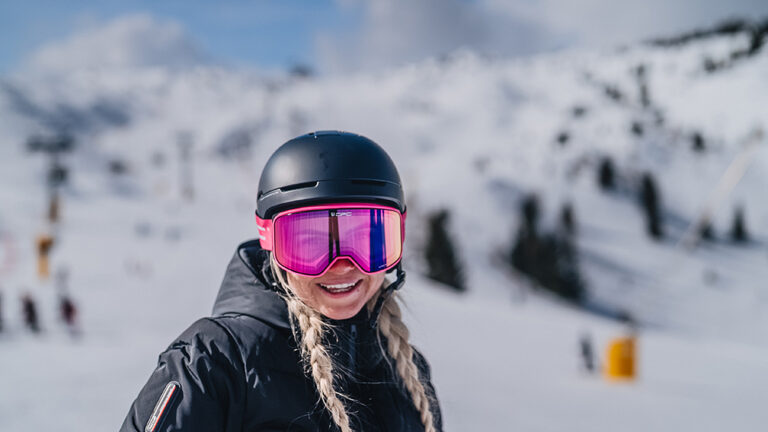 Kobieta w goglach narciarskich i kasku na stoku. Narty, snowboard, zimowy sport.