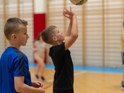 Chłopiec rzuca piłką do koszykówki na sali gimnastycznej.