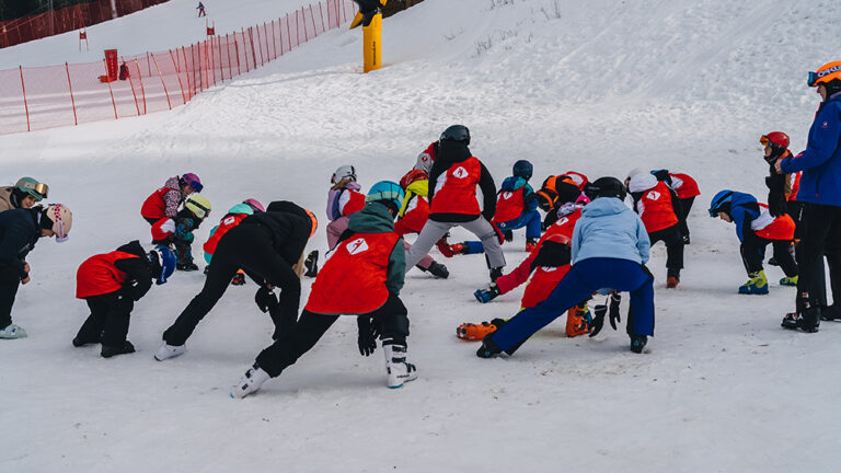 Dzieci na nartach ćwiczą na śniegu. Nauka jazdy na nartach dla najmłodszych.