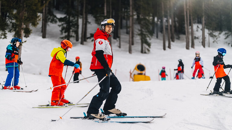Instruktor narciarstwa z dziećmi na stoku. Nauka jazdy na nartach, zimowy sport, aktywny wypoczynek.