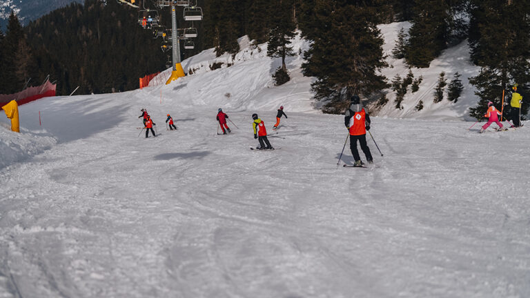 Dzieci uczą się jeździć na nartach na stoku.