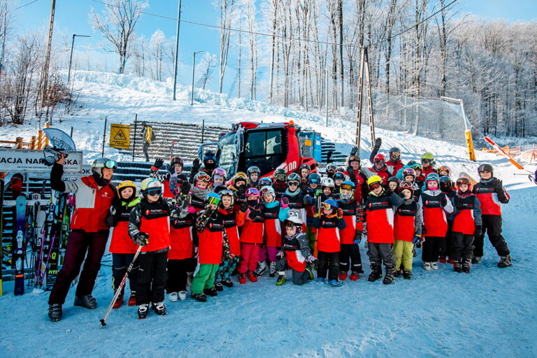 Grupa dzieci i instruktorów na stoku narciarskim, gotowi na zimowe szaleństwo.