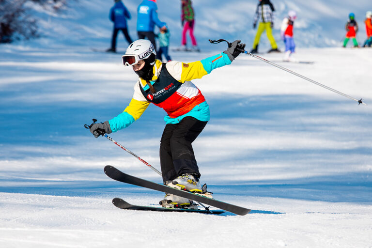 Narty, narty zjazdowe, narciarka w kolorowym stroju na stoku. Sporty zimowe, aktywny wypoczynek.
