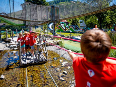 Dzieci na drewnianym moście w parku linowym. Zabawa na świeżym powietrzu.