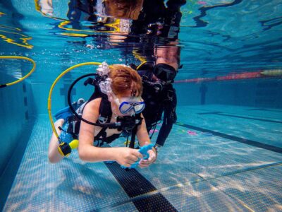 Podwodna nauka nurkowania: dziecko z instruktorem w basenie.