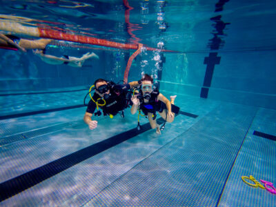 Para nurków pod wodą w basenie. Nauka nurkowania, podwodna przygoda.