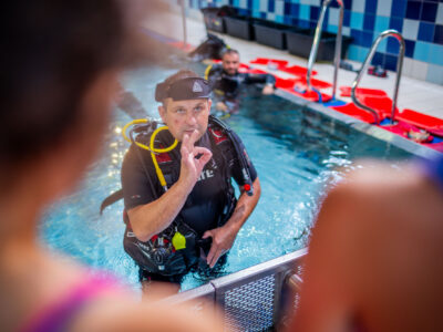 Instruktor nurkowania w basenie pokazuje znak OK. Nauka nurkowania.