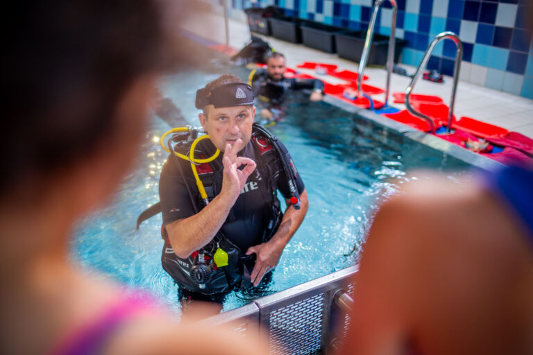 Instruktor nurkowania w basenie pokazuje znak OK. Nauka nurkowania.