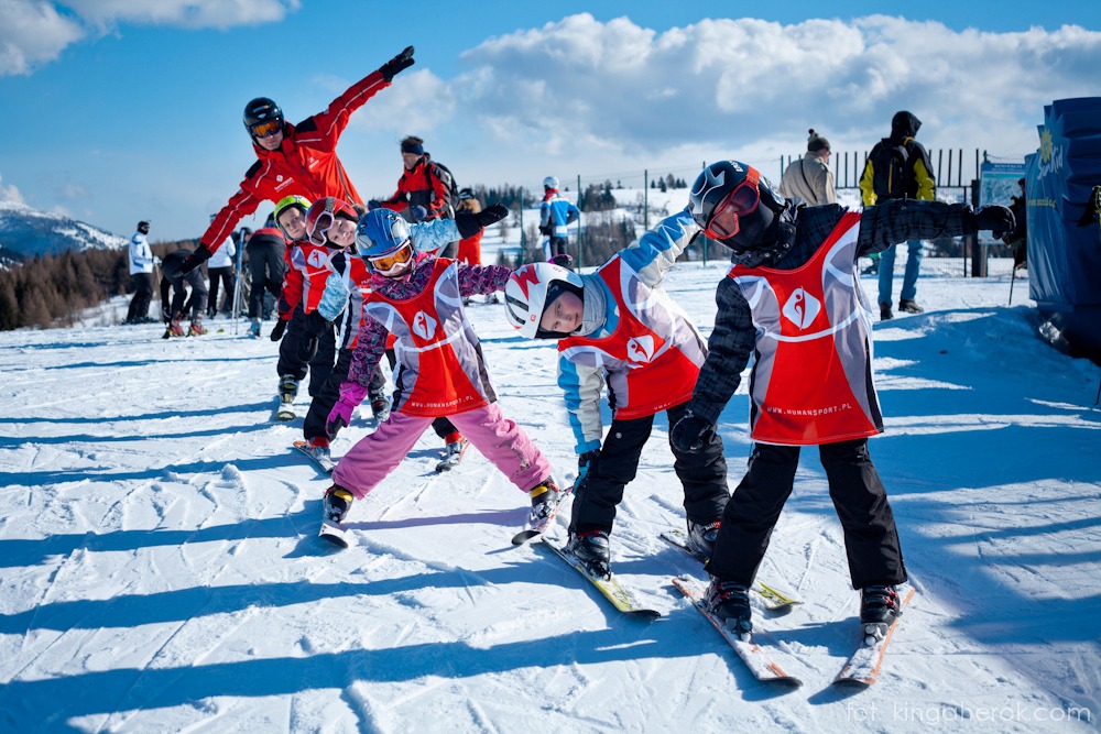 Dzieci uczące się jeździć na nartach. Zimowa zabawa na stoku.